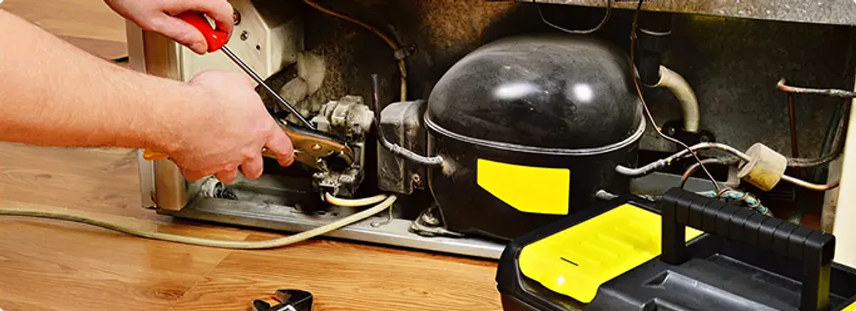 Refrigerator repair technician fixing the compressor and wiring in Berwyn, IL