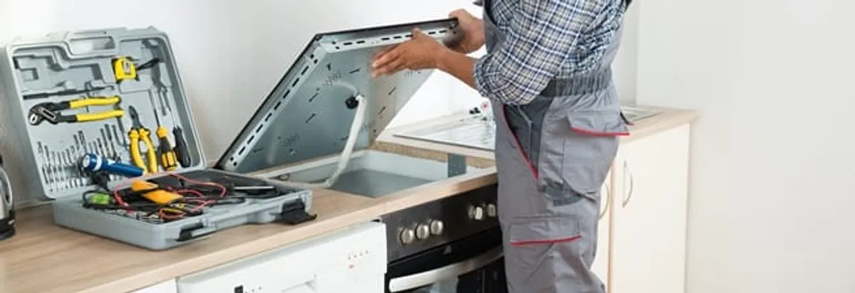 Cooktop repair technician lifting a built-in stovetop for service in Chicago, IL